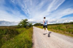 homme qui court sur la route près du champ d'herbe